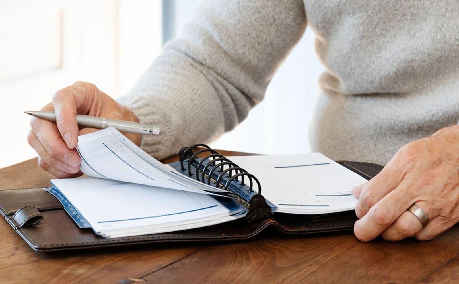 Hands turning the pages of an open Franklin planner on a desk